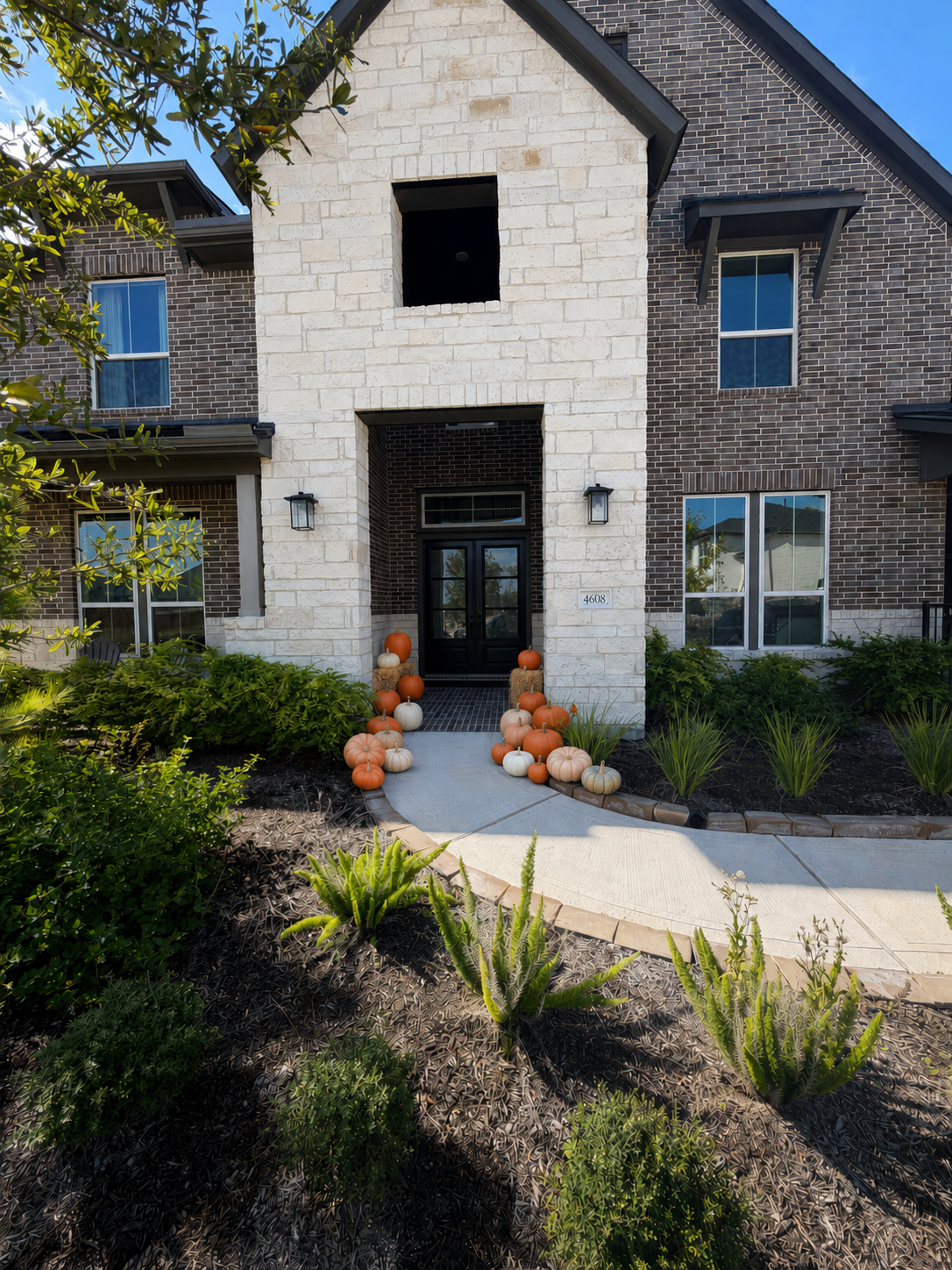 The Classic fall pumpkin porch installation with orange, white and heirloom pumpkins styled on a home in the north Houston area