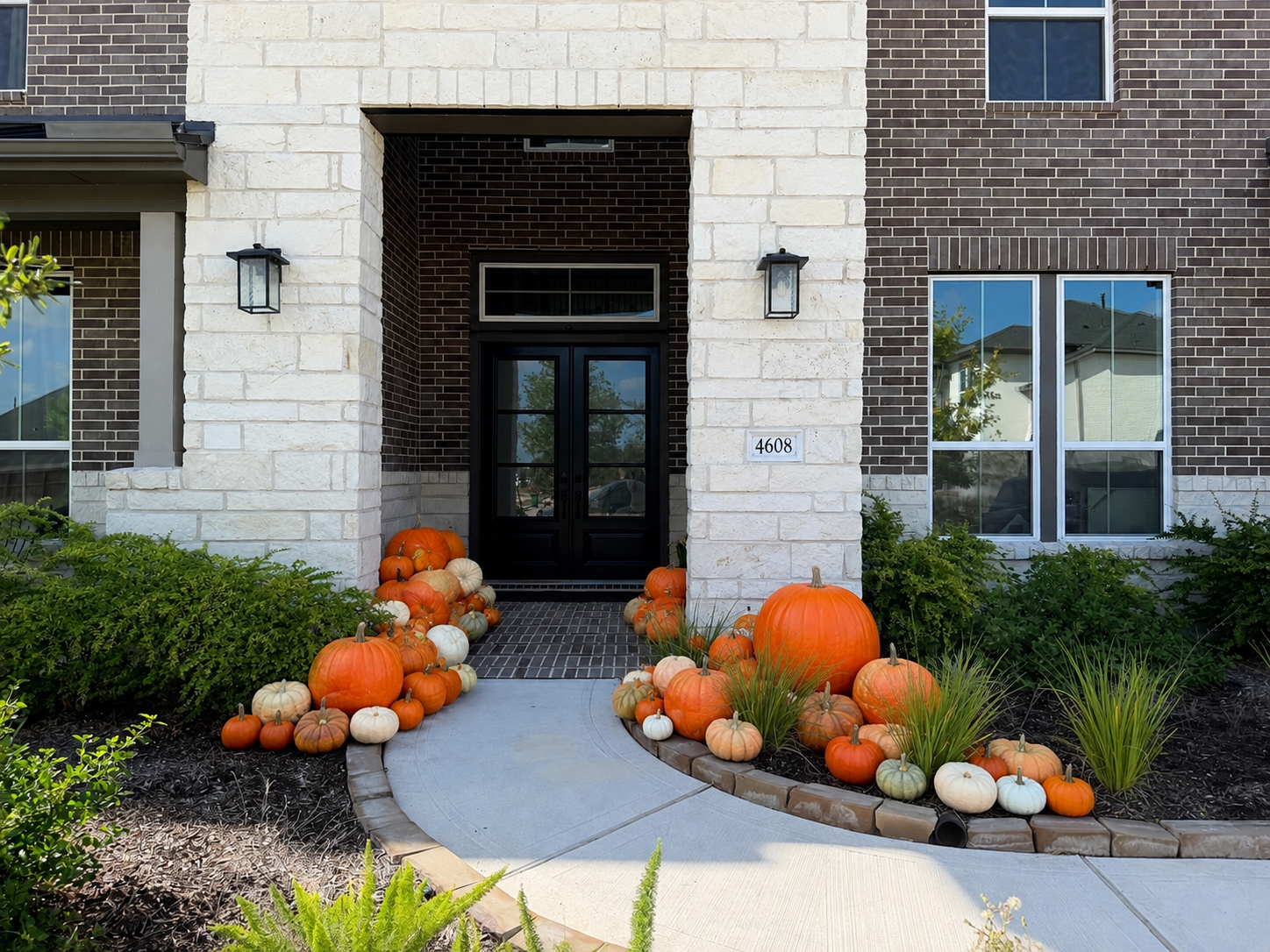 The Grand Harvest fall pumpkin porch installation with orange, white and heirloom pumpkins styled on a home in the north Houston area